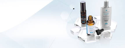 Tres frascos de productos de cuidado de la piel sobre una base transparente con un fondo claro.