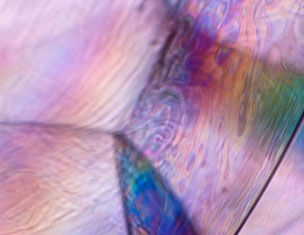 Colorful abstract patterns with iridescent swirls and smooth textures, resembling the surface of a soap bubble.