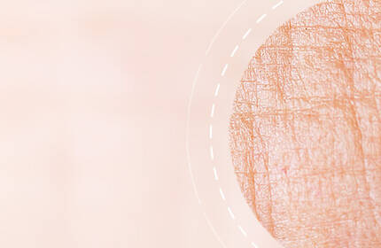 Abstract image featuring a close-up texture of skin in soft peach tones, with a circular section highlighting fine lines and creases.