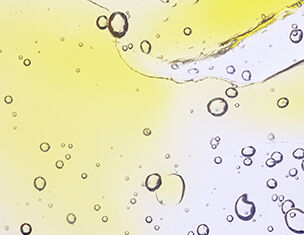 Burbujas de aire flotando en un liquido amarillo claro, creando un efecto visual dinamico y transparente.