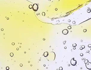 Burbujas de aire flotando en un liquido amarillo claro, creando un efecto visual dinamico y transparente.