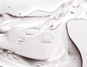 Primer plano de gotas de agua sobre una superficie brillante y suave que refleja la luz.