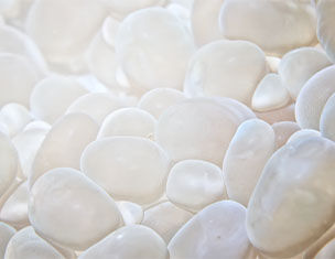 Piedras blancas y brillantes dispersas sobre una superficie clara, creando un efecto suave y luminoso.