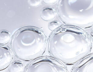Burbujas de agua transparentes en un fondo claro, creando un efecto visual brillante y ligero.