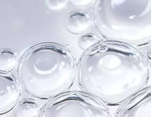 Burbujas de agua transparentes en un fondo claro, creando un efecto visual brillante y ligero.