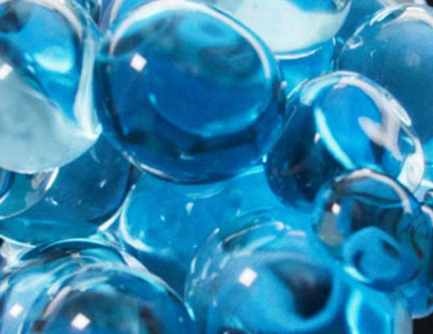 Close-up of shiny blue marbles with varying shades and translucence, creating a visually striking pattern.
