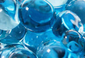 Close-up of shiny blue marbles with varying shades and translucence, creating a visually striking pattern.