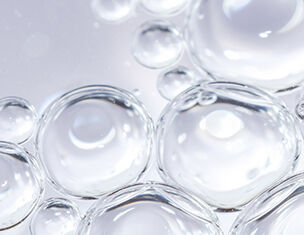 Burbujas de agua en un fondo claro, destacando la transparencia y la forma esferica de las burbujas.