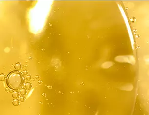 Primer plano de burbujas en un liquido amarillo, con luz reflejada que aporta un brillo suave y calido.