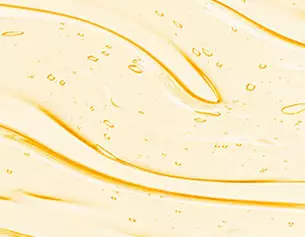 Textura de un liquido amarillo con burbujas, que se despliega sobre una superficie, creando ondas suaves y brillantes.