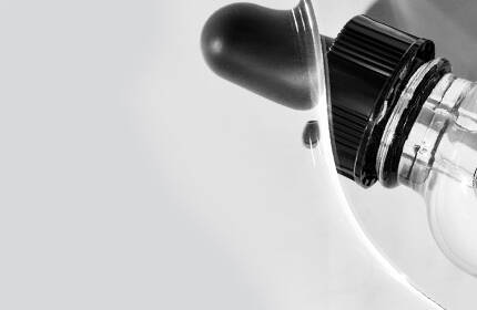 Close-up of a white device with a black knob and a transparent component, set against a light gray background.