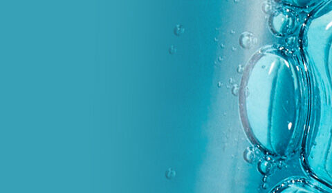 Close-up of a blue liquid with bubbles, contrasted against a white background.