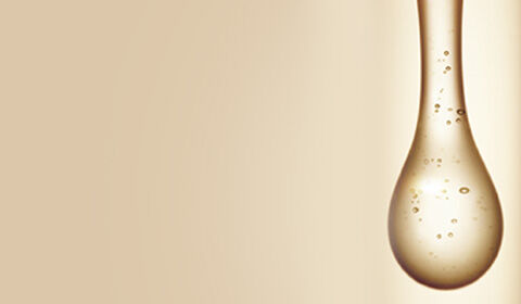Abstract image of a fluid droplet with bubbles, set against a light tan background. The droplet features a smooth, elongated shape tapering to a point.