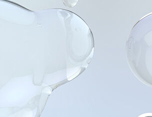 Gotas de liquido transparente sobre un fondo claro, generando un efecto visual suave y etereo.