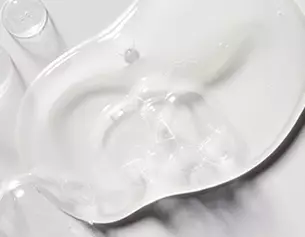 Close-up of a clear, viscous gel on a smooth surface, highlighting its shiny and reflective texture.