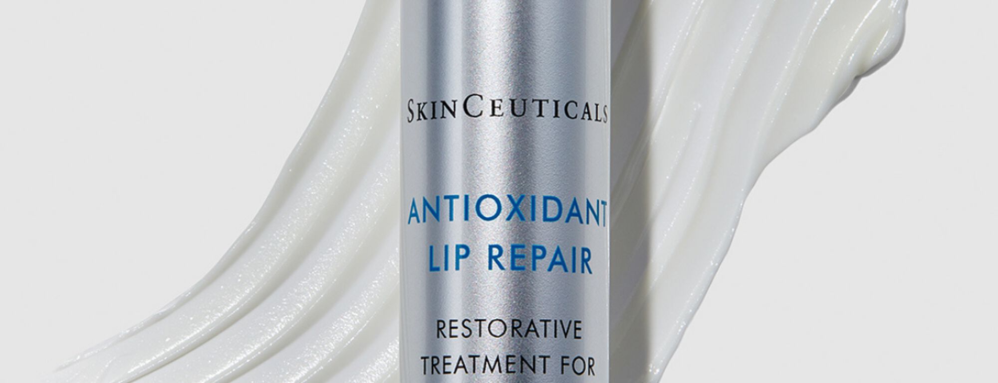 Tratamiento restaurador para labios de SkinCeuticals, con un fondo de crema blanca suave.