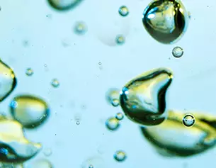 Gotas de aceite y burbujas en un fondo azul claro, creando un efecto visual atractivo y abstracto.