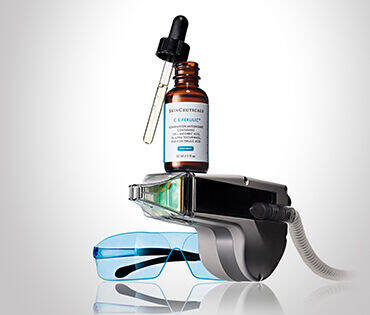 Frascos de suero y gafas de proteccion sobre un dispositivo de tratamiento facial.