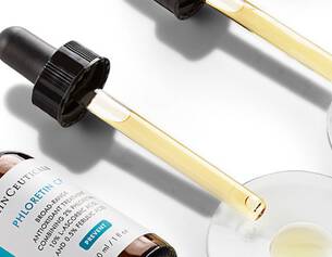 Botellas de suero Skinceuticals con goteros y muestras en platos, destacando su color y textura.