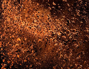 Textura de una superficie metalica oxidada, con tonos marrones y anaranjados y un patron irregular de corrosion.