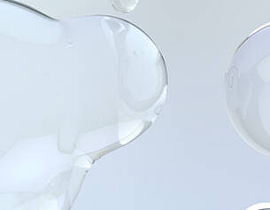Texto alternativo: Gotas de liquido transparente sobre un fondo claro, creando un efecto visual suave y fluido.