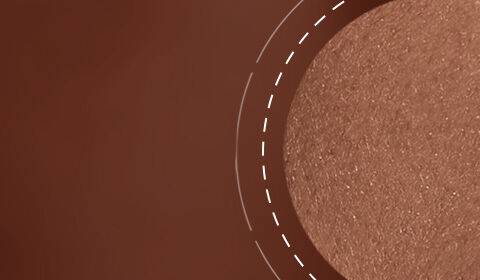 Close-up of a smooth, shimmering bronzer in a warm brown shade, set against a blurred background.