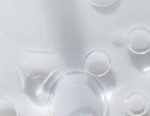 Burbujas de agua en una superficie blanca, creando un efecto visual suave y limpio.