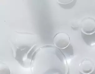 Burbujas de agua en una superficie blanca, creando un efecto visual suave y limpio.