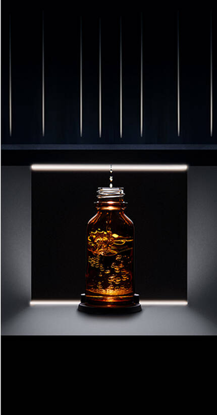 Botella de vidrio oscura con un liquido dorado iluminada suavemente en un entorno oscuro.