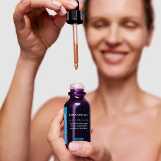 Mujer sostiene el serum HA Intensifier de Skinceuticals