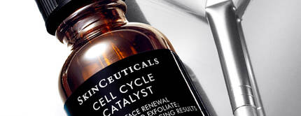 Botella de suero SkinCeuticals Cell Cycle Catalyst con un gotero, sobre una superficie reflejante. El envase destaca por su etiqueta que describe sus propiedades de renovacion y anti-envejecimiento.