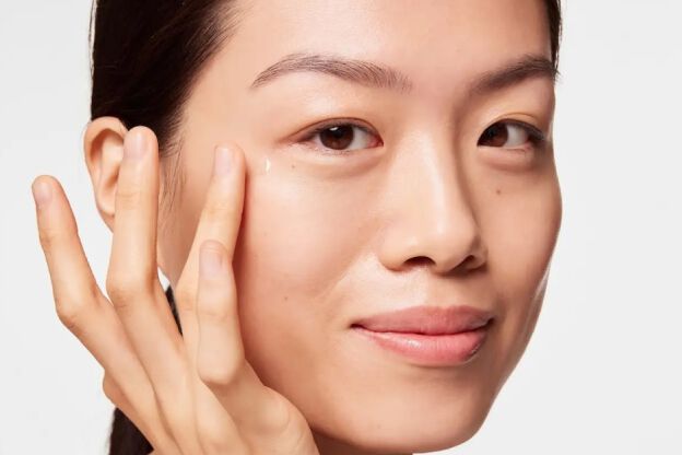 Mujer aplicando un producto cosmetico hidratante de SkinCeuticalsen su rostro.  Se enfoca en la aplicacion del producto en la zona del contorno de ojos.