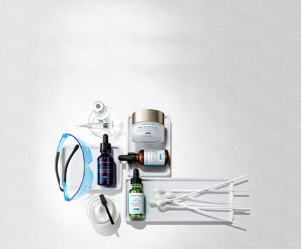 Imagen que muestra una variedad de productos de cuidado de la piel, incluyendo frascos de suero, cremas y utensilios de aplicacion sobre una superficie blanca.