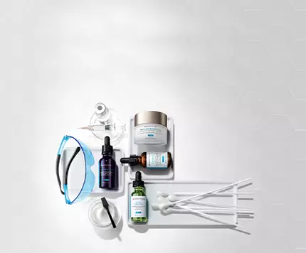 Imagen que muestra una variedad de productos de cuidado de la piel, incluyendo frascos de suero, cremas y utensilios de aplicacion sobre una superficie blanca.