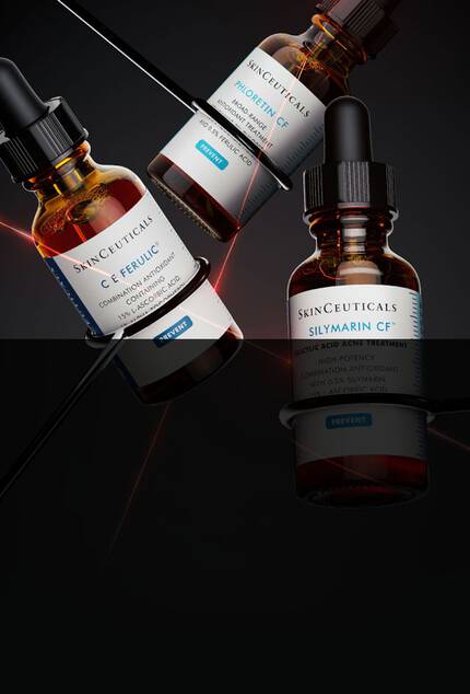 Tres botellas de suero, con etiquetas de "SkinCeuticals", sobre un fondo oscuro. Una de las botellas esta inclinada, mientras que las otras dos estan en posicion vertical.