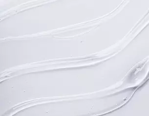 Swirls of white cream or gel texture on a smooth surface, showcasing a glossy and fluid appearance.