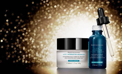 A collection of SkinCeuticals skincare products, including A.G.E. Interrupter Ultra Serum and A.G.E. Interrupter Advanced all set against a shimmering gold background.
