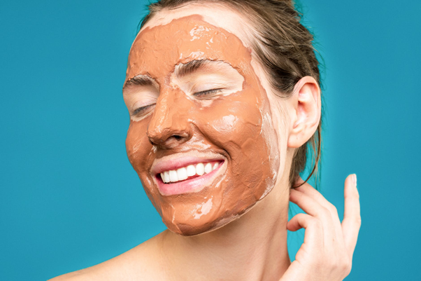 Mujer sonriendo con mascarilla de arcilla en la cara