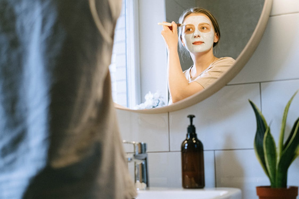 Mujer aplicando mascarilla de arcilla verde en el rostro