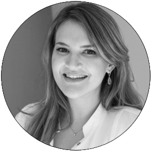 Retrato en blanco y negro de una mujer sonriendo, con cabello largo y suelto, vestida con una blusa blanca y aretes.